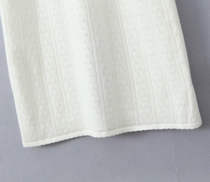 Gros plan d'une robe en maille blanc crème montrant des détails de texture jacquard