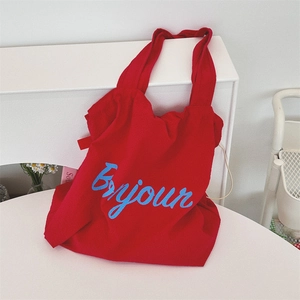Close-up of red nylon tote bag featuring blue Bonjour embroidery for summer travel