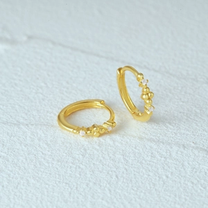 Macro shot of gold-plated S925 silver hoop earrings with sparkling cubic zirconia inlay