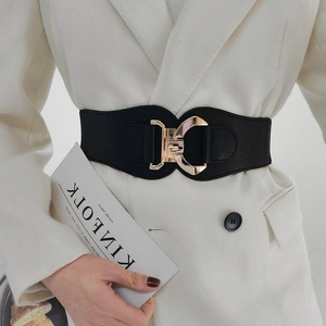 Women's wide elastic corset belt with geometric gold metal buckle on white blazer