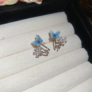 Gros plan de boucles d'oreilles papillon bleues et fleurs avec strass dans un coffret