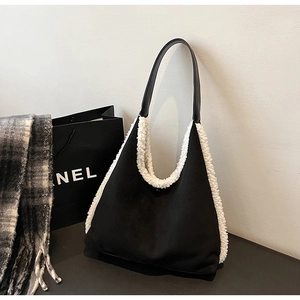 Close-up of black plush shoulder bag featuring thick white faux fur trim and leather strap