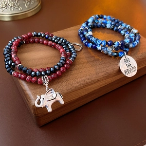 Detail of beaded bracelets with elephant charm and engraved and she persisted silver tag