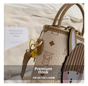 Detail of beige bucket bag with bear print and cute bunny charm on gold hook