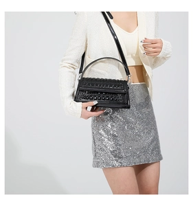 Detail of black crocodile texture handbag featuring silver hardware and a round top handle
