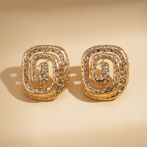 Detailed macro view of gold-plated square spiral earrings with a hammered texture finish