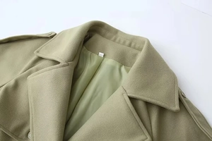 Detailed close-up of wide lapels and shoulder tabs on a sage green wool blend coat