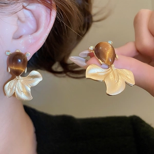Detailed close-up of fish tail stud earring with brushed metal finish and cat-eye stone
