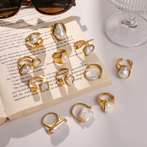 Golden rings with irregular baroque pearls displayed on a vintage open book background