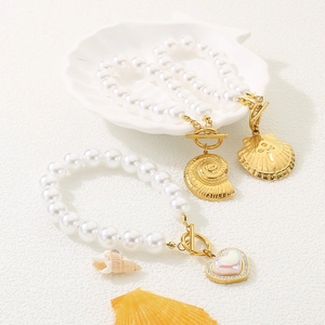 Detailed shot of white pearl bracelets with gold shell charms and rhinestone heart pendant