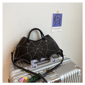 Detail of black PU leather bat-shaped handbag with white spiderweb stitching and metal spider