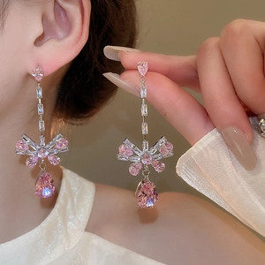 Detail of silver drop earrings with pink crystal and elegant bow design for women