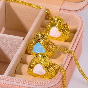 Golden heart locket necklace with opal inlay and floral relief in a pink jewelry box