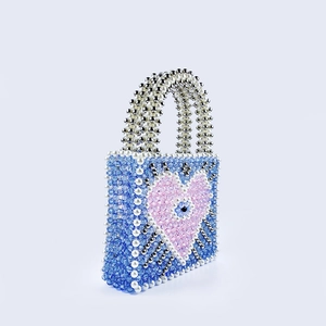 Macro view of blue beaded handbag featuring evil eye heart pattern and pearl handles