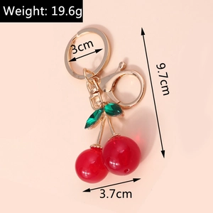 Detail view of red cherry keychain with dimensions and weight on pink background