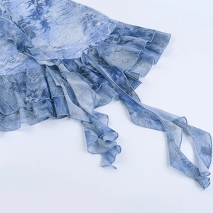 Détail d'une mini robe tie-dye bleue avec bords à volants et fines bretelles