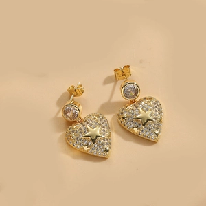 Close-up of golden heart and star drop earrings with sparkling pavé crystals
