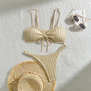 Detailansicht eines cremefarbenen Bikinis mit geraffter Textur auf weißem Plüschstoff