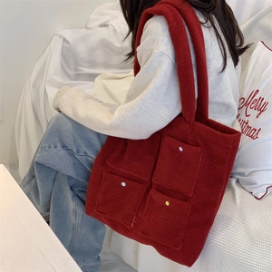 Detail of red felt tote bag with multi-pocket design and decorative buttons for winter