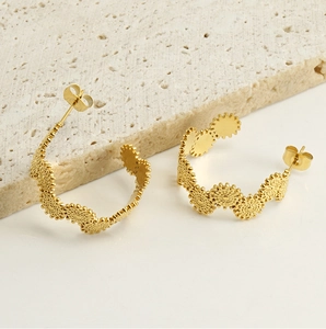 Détail de boucles d'oreilles C en acier doré 18 carats avec bords dentelés texturés