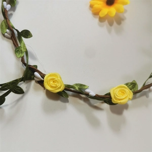 Detailed close-up of yellow ribbon roses with green leaves on a brown floral headband