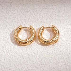 Detailed shot of gold hoop earrings featuring a unique hammered molten texture finish
