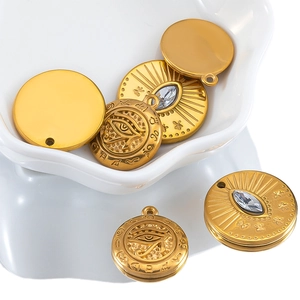 Macro view of gold stainless steel charms with Horus eye engraving and zircon inlays