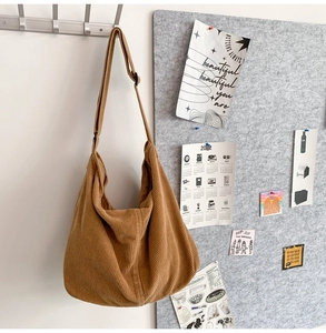 Brown corduroy crescent shoulder bag hanging on a wall with creative aesthetic background