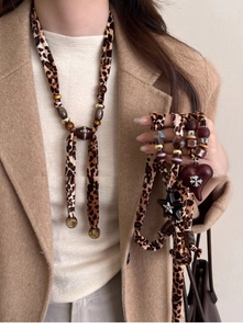 Detail of leopard print fabric necklace with heart and star pendants on a winter coat