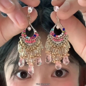 Detailed view of bohemian gold tassel earrings with colorful rhinestones and pink pendants