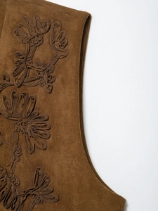 Detail of floral embroidery on brown faux suede vest showing texture and craftsmanship