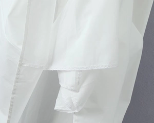 Detailed close-up showing the hem stitching and folded edge of white woven cotton skirt