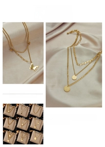 Detail of layered gold necklaces with butterfly pendants and pearls on silk fabric