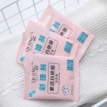 Detail showing three bags of pink oxygen laundry bleach powder on white knit fabric
