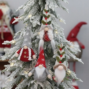 Set of 4 handmade Christmas gnome ornaments with knitted hats on a festive snowy tree