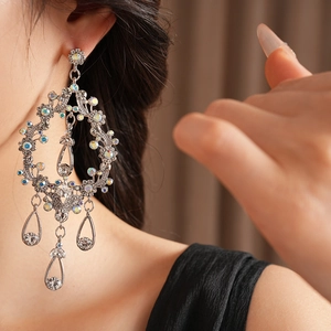 Macro shot of silver teardrop tassel earrings with sparkling crystals on a model's ear