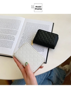 Quilted leather card holders in black and white with gold zippers on a table