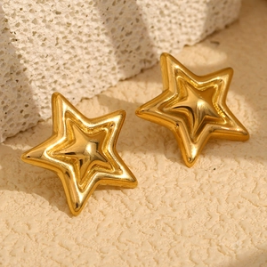 Detailed view of 18K gold plated triple layered star stud earrings on stone texture