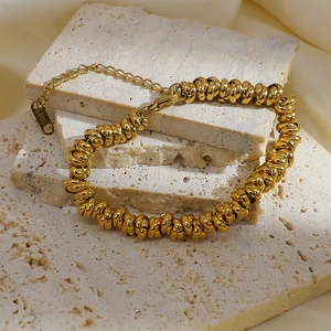 Detailed macro view of gold plated stainless steel chain on textured stone and silk