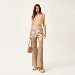 Sleeveless crop top with X embroidery and metallic gold flare jeans on model