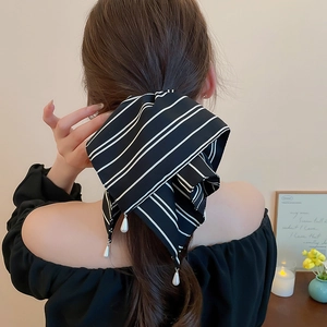 Détail d'un foulard à rayures noires et blanches avec pendentif perle sur modèle