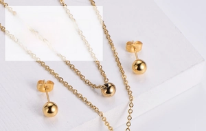 Detailed view of gold ball jewelry set including polished round stud earrings and necklace
