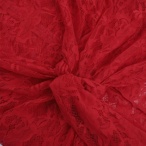Close-up of red lace fabric texture with knotted design for elegant long sleeve dress