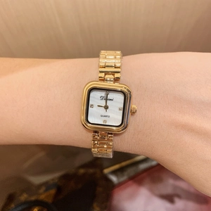 Detail of a square gold watch with mother-of-pearl dial and diamond markers on the wrist