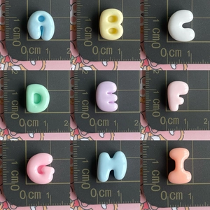 Candy colored resin alphabet beads A-I set on a ruler showing 1.5cm mini size