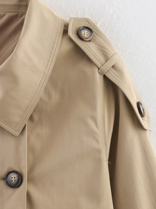Detail of shoulder epaulettes and double-stitched lapel on khaki trench coat