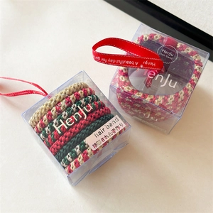Detailed view of handmade Christmas hair tie set in a clear box with festive red ribbons