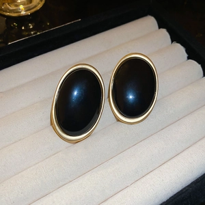 Vue macro de boucles d'oreilles ovales vintage avec résine noire et monture dorée