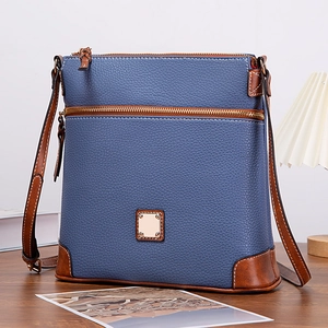 Detail of blue lychee grain leather crossbody bag with brown trim and dual gold zippers