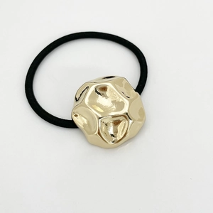 Detailed view of the gold irregular geometric metal ornament on a black elastic hair tie